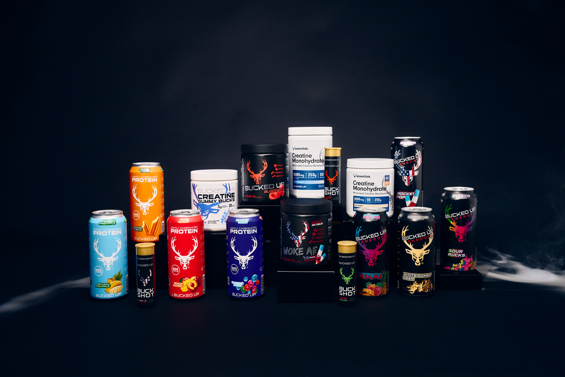 Collection of Bucked Up supplements including Woke AF pre-workout, Bucked Up energy drinks, Buck Shot, creatine, and protein powders displayed on dark background – premium fitness and performance products lineup.