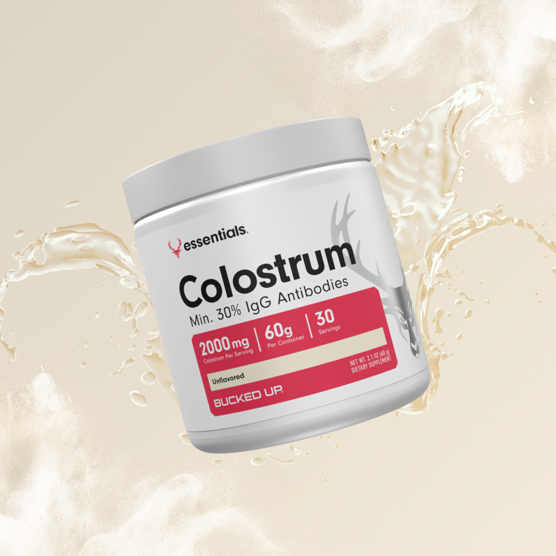 Product image of Bucked Up Essentials Colostrum supplement jar, labeled 'Min. 30% IgG Antibodies,' 2000mg per serving, unflavored, with dynamic liquid splash background.