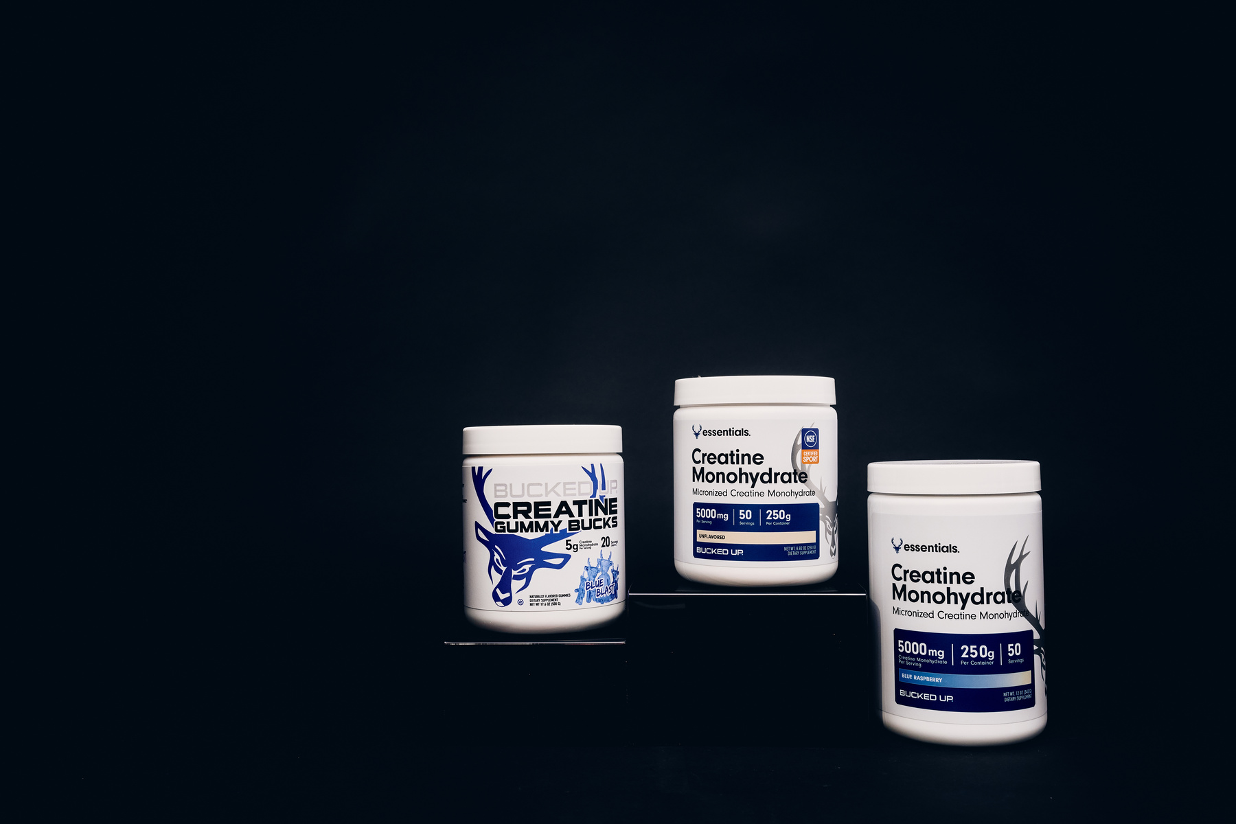 Bucked Up Creatine Gummy Bucks and Essentials Creatine Monohydrate supplements displayed on black background – muscle strength and performance support products.